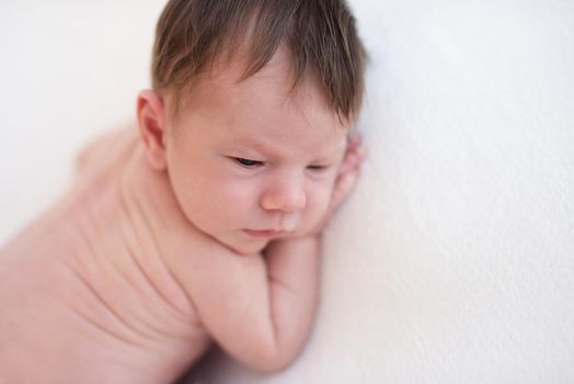 Innocent naked newborn lying awake on stomach