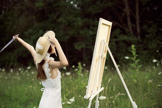 pretty woman artist paints a picture on nature landscape. High quality photo