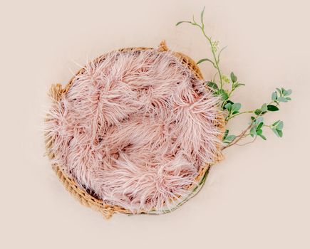 Beautiful backdrop for newborn photosession with flowers hydrangea. Digital composite with basin filled with knitted blanket isolated on light pink background. Top view