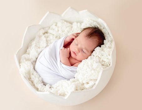 Cute newborn resting in egg cradle