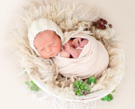 Charming awake newborn lying in cradle wrapped in blanket