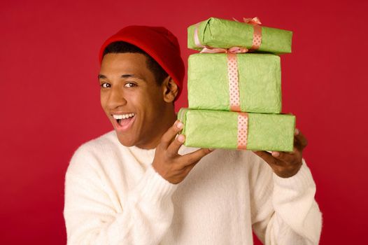 Christmas gifts. Young guy in santa hat holding gifts