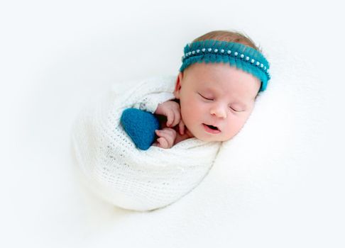 Sleeping newborn baby girl wrapped in white blanket