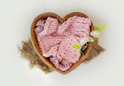 Wooden bed heart decor for newborn studio photoshoot with knitted blanket closeup