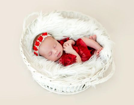 Sleeping newborn baby girl in a red dress