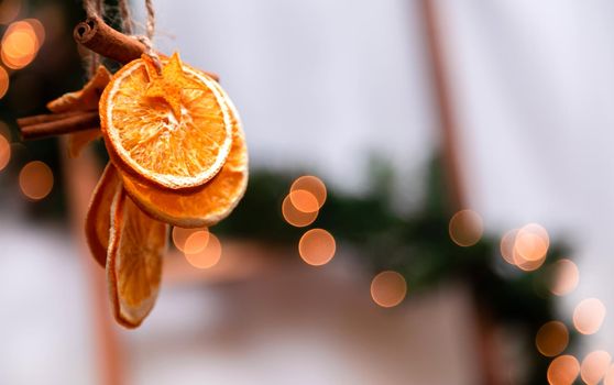 Hanging Christmas decoration of dried oranges, tangerine and cinnamon stars with copy space for text. holiday concept. blurred background.