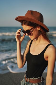 cheerful woman in sunglasses and a hat by the ocean walk summer. High quality photo