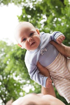 Father plays with son in a park. Flying baby