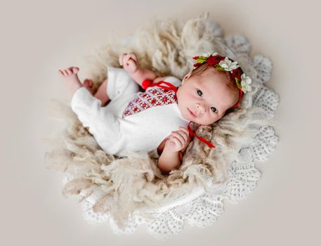 Sleepless newborn in embroidered suit and floral diadem