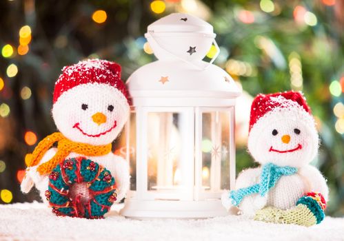 Knitted snowmen and Christmas lantern-candlestick - home decorations on the snow