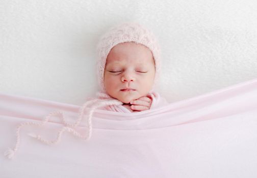 Sleeping newborn baby girl wrapped in white blanket