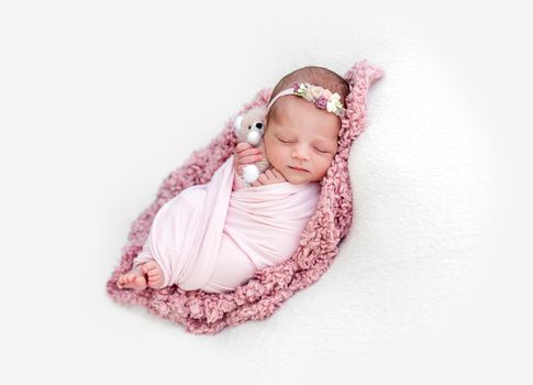 Sleeping newborn baby girl wrapped in pink blanket
