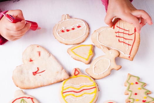 Hands of little girl, who draws on gingerbread cookies