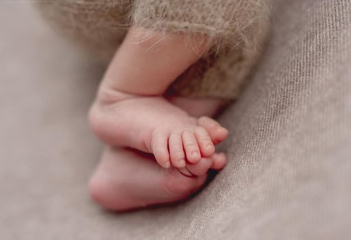 Little newborn baby legs on a warm plaid