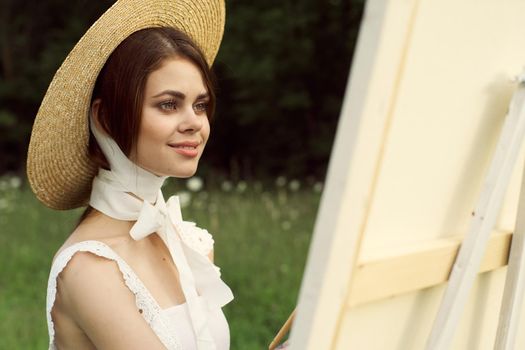 Woman in white dress outdoors artist drawing easel. High quality photo