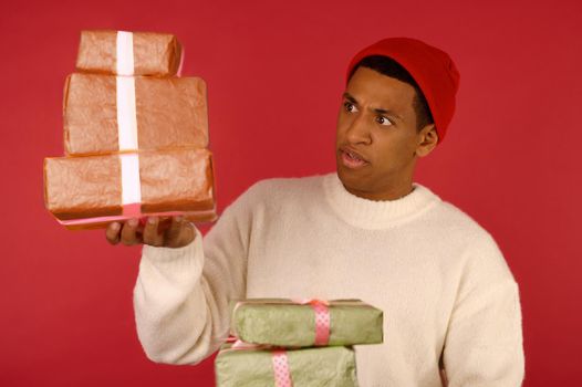Christmas mood. A dark-skinned excited young guy with a gift boxes in hands
