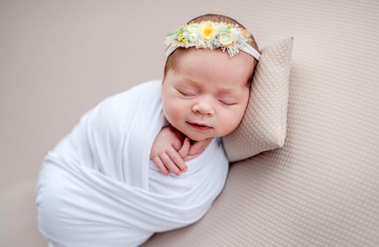 Smiling newborn in floral rim sleeping on tiny pillow