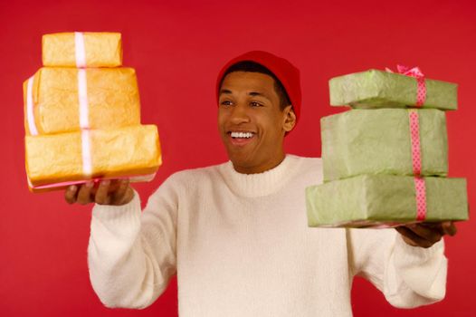 Christmas mood. A dark-skinned excited young guy with a gift boxes in hands