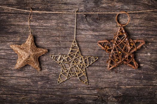 Brown christmas decorations attached to the rope, over wooden background