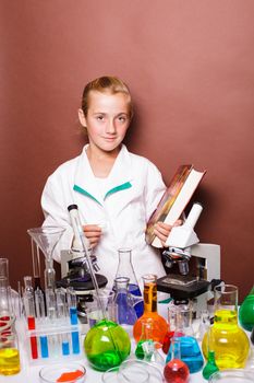 Schoolgirl with chalk standing near blackboard in the laboratory classes in chemistry