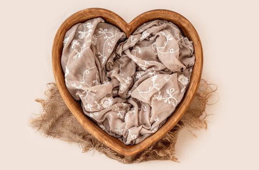 Beautiful wooden heart furniture bed for newborn studio photoshoot with sheets. Tiny designed place for infant photo isolated on light background