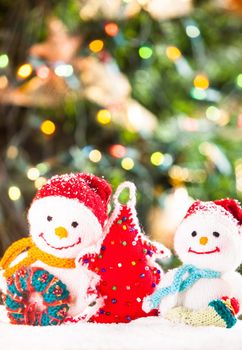 Knitted snowmen and handmade Christmas tree - home decorations on the snow