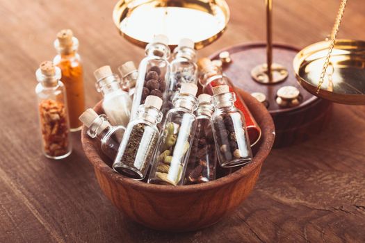 Little bottles with spices in a wooden bowl in the kitchen. Retro decorations