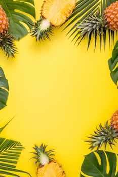 Beautiful pineapple on tropical palm monstera leaves isolated on bright pastel orange yellow background, top view, flat lay, overhead above summer fruit.