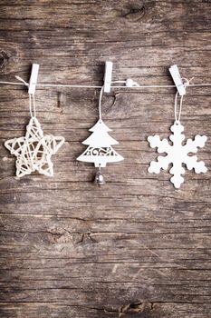 White christmas decorations attached to the rope, over wooden background