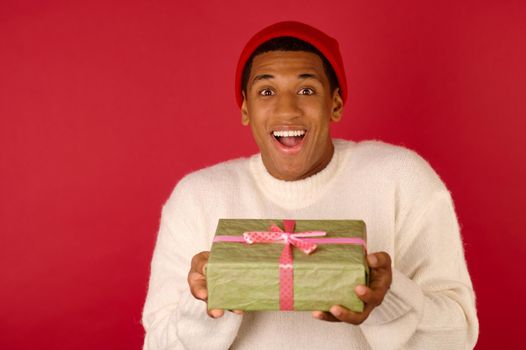 Xmas present. A dark-skinned young guy with a gift box in hands