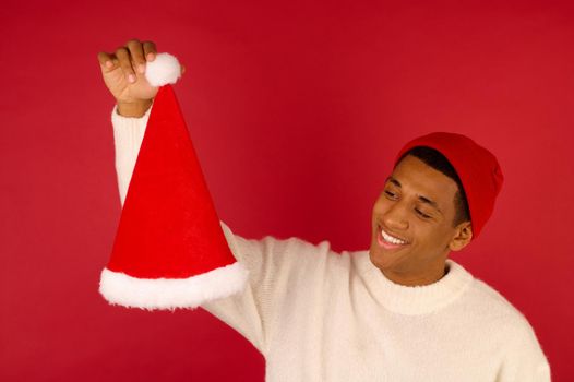 Ready for Xmas. Young smiling guy with santa hat with in hand