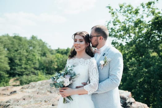 Wedding photo of the bride and groom in a gray-pink color on nature in the forest and rocks