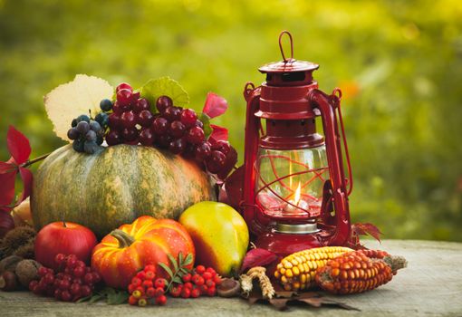 Fruits and nuts, pumpkins on the table outdoor and kerosene lamp - cozy autumn