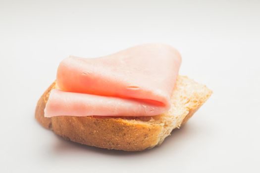 Fresh rolled ham slice and breadon a white plate close up