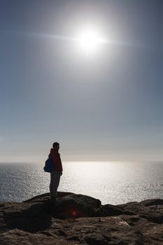 silhouette of man standing on the sun at Cape Finisterre with sea on background. Mountain ocean shore, rocky beach