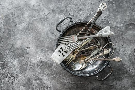 Big rustic bowl with cute designed antique dishware, spoons and forks, copyspace, topview