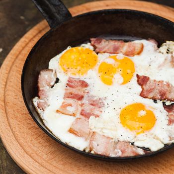 Fried bacon and eggs on the pan - rusty breakfast