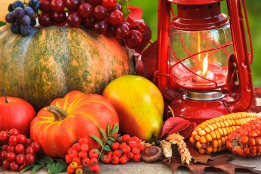 Fruits and nuts, pumpkins on the table outdoor and kerosene lamp - cozy autumn