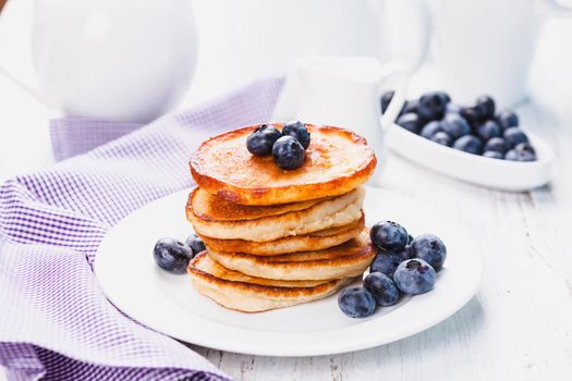 Pancakes with blueberry on a white plate and napkin