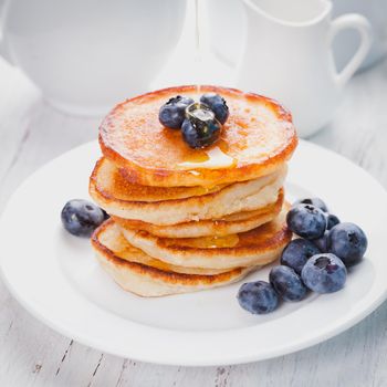 Pancakes with blueberry and honey on a white plate