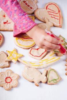 Hands of little girl, who draws on gingerbread cookies