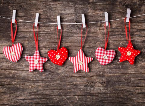 White and red sewed christmas decor attached to the rope, over wooden background