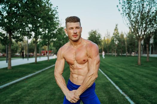 sporty man with muscular body pumping in park workout. High quality photo