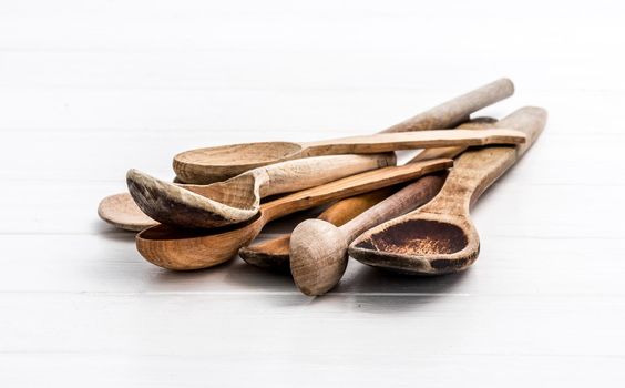 Bunch of rustic brown natural wooden spoons on white background