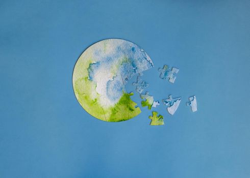 unfinished jigsaw puzzle in shape of globe on blue background. Protecting the planet concept