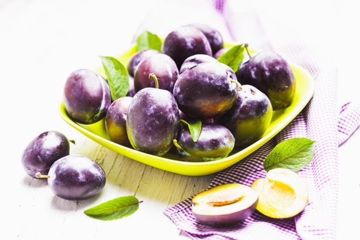 Fleshy plums in a bowl on the table