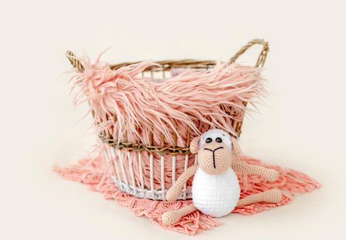 Tiny basket decor for newborn studio photoshoot filled with fur and knitted toy closeup. Infant baby handmade furniture