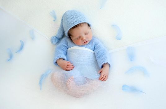 Sweet newborn baby boy sleeping wearing knitted costume and hat. Napping infant kid studio portrait