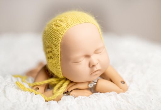 Realistic plastic figure of newborn child for photographing practice, with head on hands