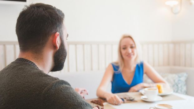 Young caucasian man in front of woman spending time in the cafe, close up